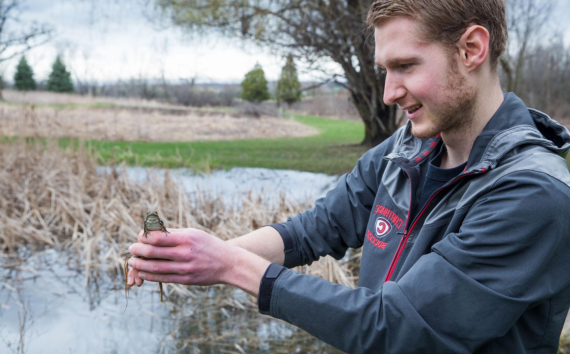 An environmental science major holding a toad while doing research.